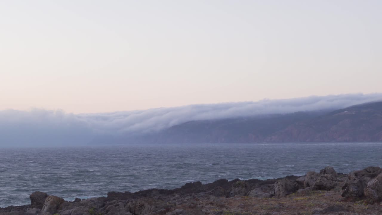 Clouds Rolling over the Mountains into the Sea at Guincho Beach in Portugal