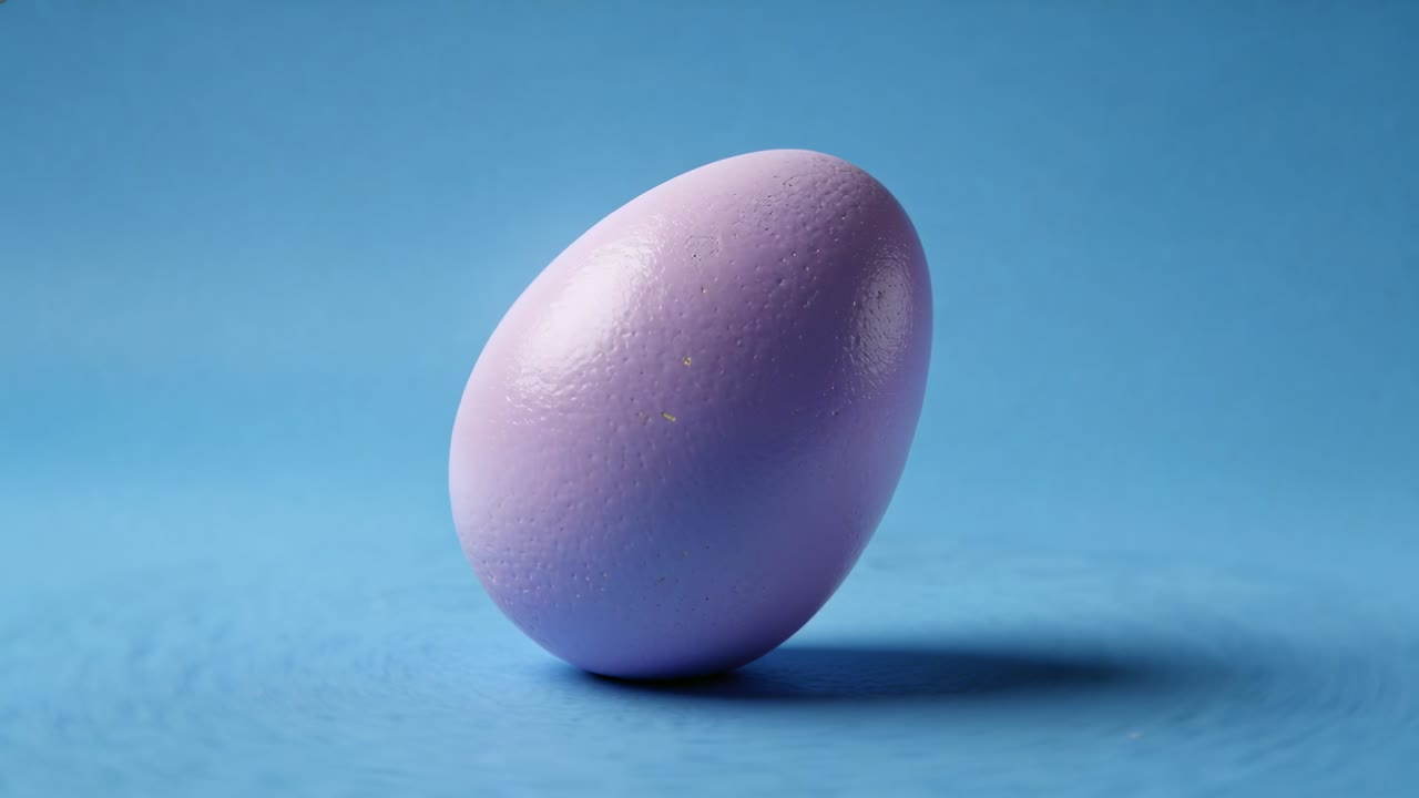 Tilting single painted egg rolling to rest on blue surface due to slight imbalance, showing shadow