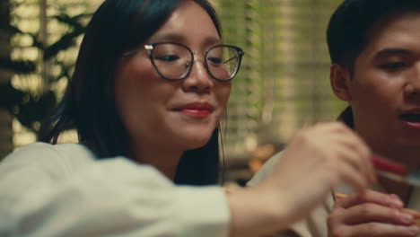 smiling young woman with glasses serving food in a cozy indoor setting