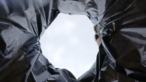 low angle responsible male dropping plastic bottle into garbage recycling waste bag