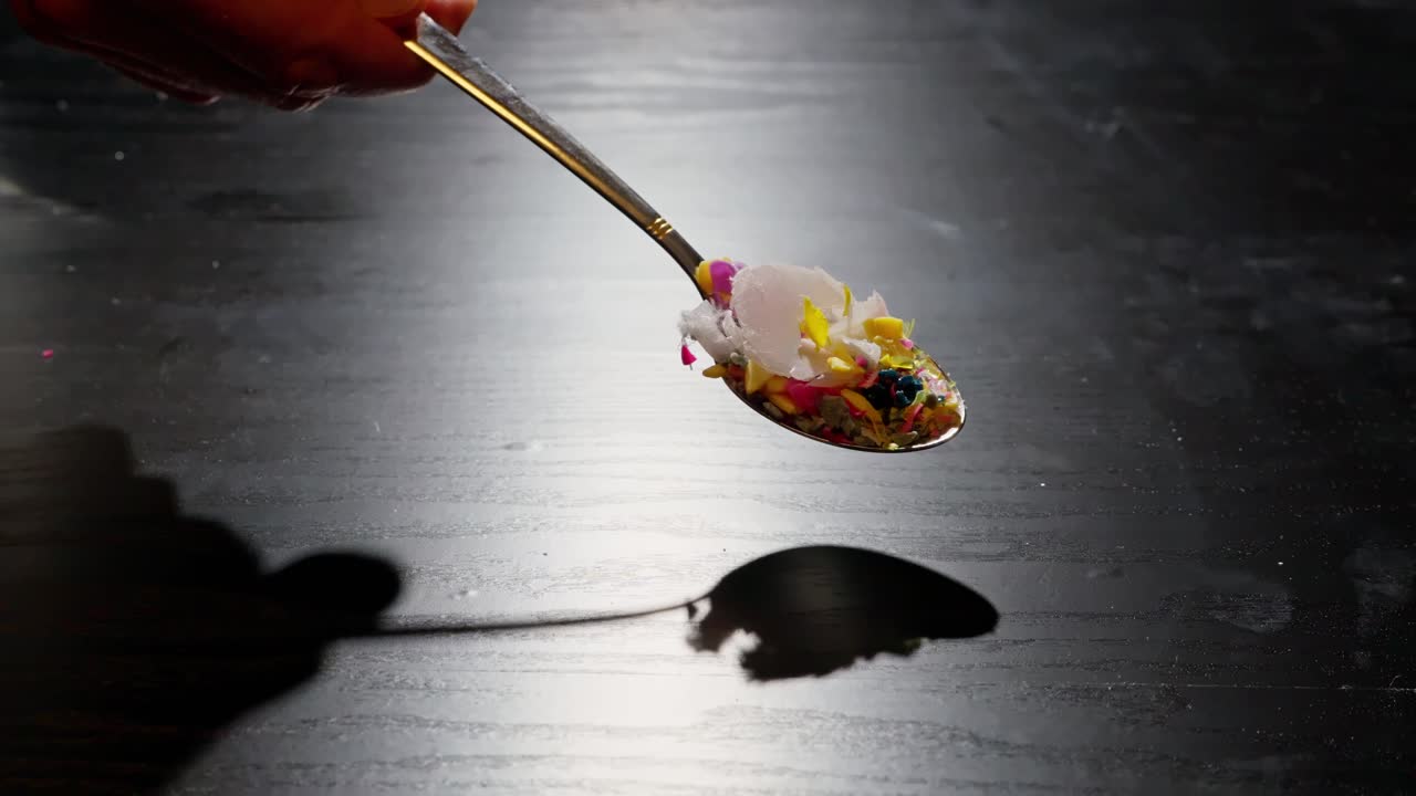 la cuchara esparce escombros de plástico sobre la mesa, simbolizando la contaminación por microplásticos, los riesgos para la salud y el daño ambiental