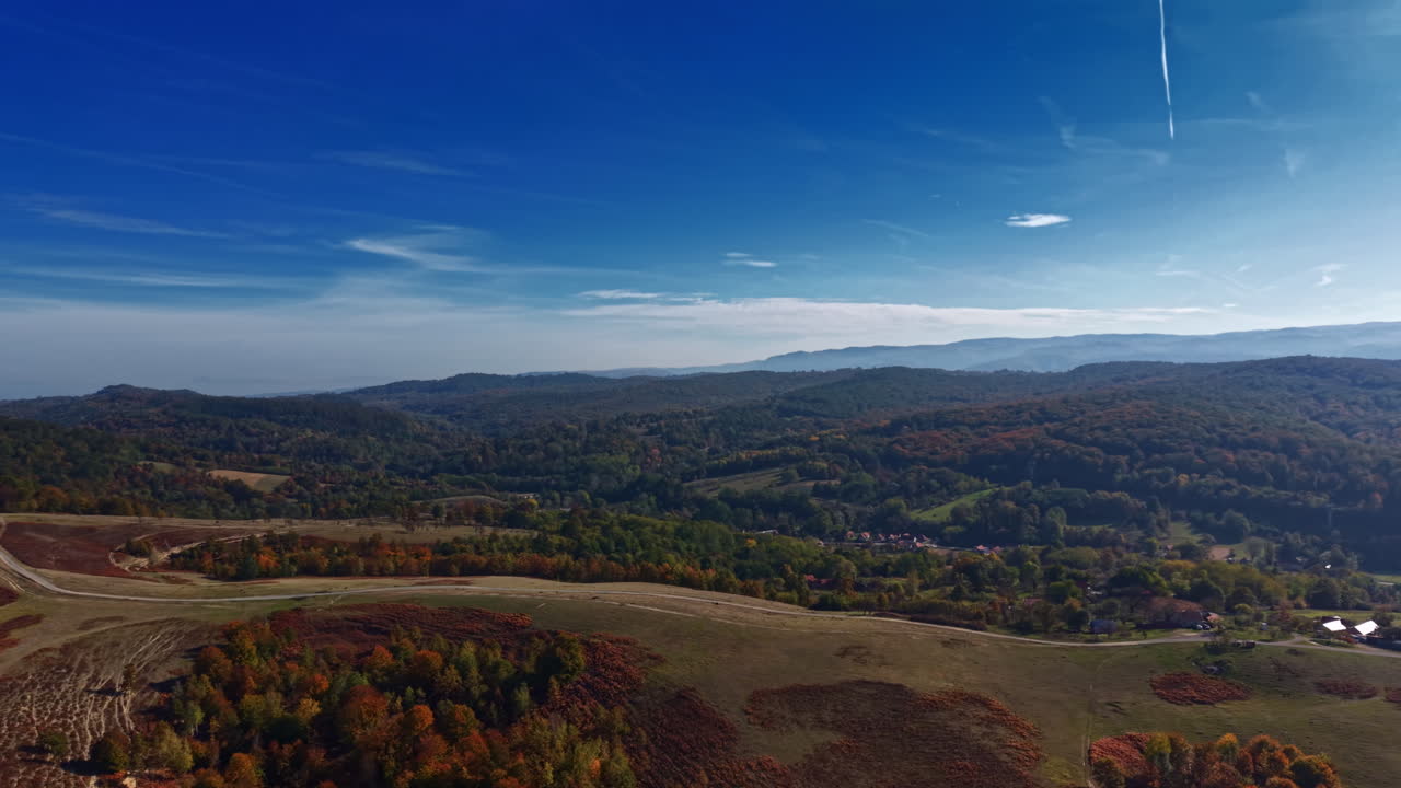 Scenic autumn landscape with rolling hills and colorful foliage under a clear blue sky in the countryside