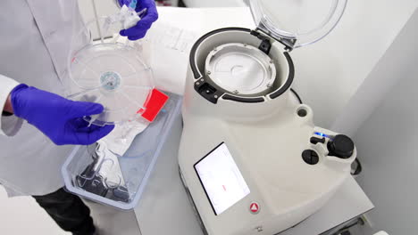 unrecognized male medic wearing white robe and blue latex gloves takes a system for blood sampling. high angle view at the doctor preparing for prp-therapy.