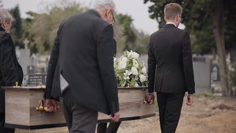 Coffin,-men-and-pallbearers-walking-at-graveyard