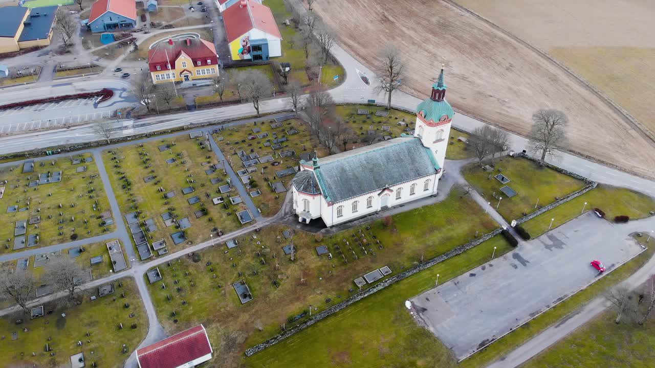 vista aérea del edificio de la iglesia blanca sobre un exuberante césped verde con árboles sin hojas cerca de la calle