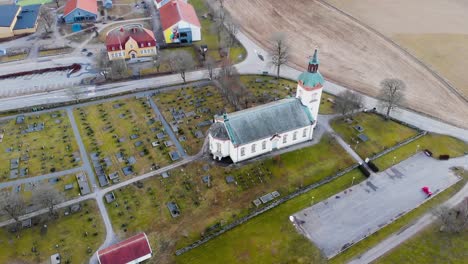 aerial view of white church building on lush green grass with leafless trees near the street