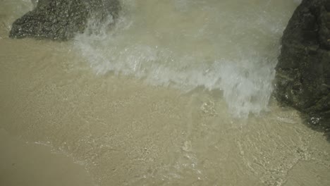 waves lapping on pristine sandy beach with interesting rock formations