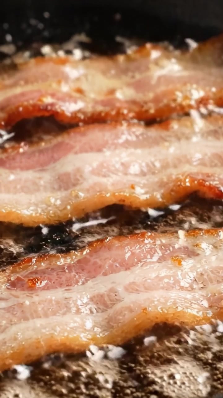 Spruttende bacon steger på en pande: Fanger den gyldne, sprøde tekstur og den spændende aroma af perfekt stegte baconstrimler midt i herligt fedt og smag