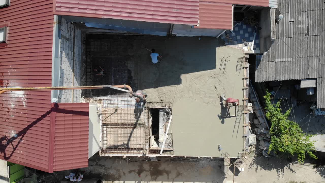 Bidikan drone udara dari atas pekerja yang menuang beton di musim panas