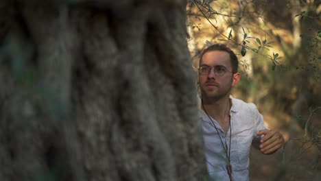 Young-male-naturalist,-free-hippie-man-hugging-and-embracing-tree-in-forest