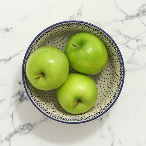 green apples in bowl on white marble table  top view