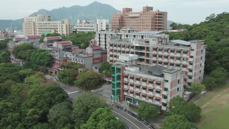 urban landscape in taiwan, showing a mix of residential buildings, trees, and mountains in the background, aerial view