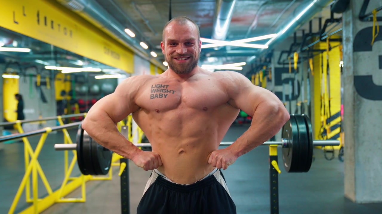 Bodybuilder muscoloso che posa e sorride in una palestra moderna