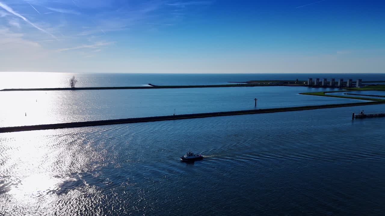 Boat floating by the waterscape sparkling in the sun. Aerial view on the Merkemeer Lake with dams and sluices. Lelystad, the Netherlands.