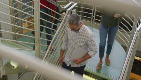 Diverse-male-and-female-business-colleagues-walking-on-stairs