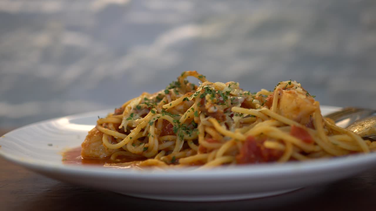 작은 소녀가 레스토랑에서 토마토 해산물 스파게티를 먹습니다.