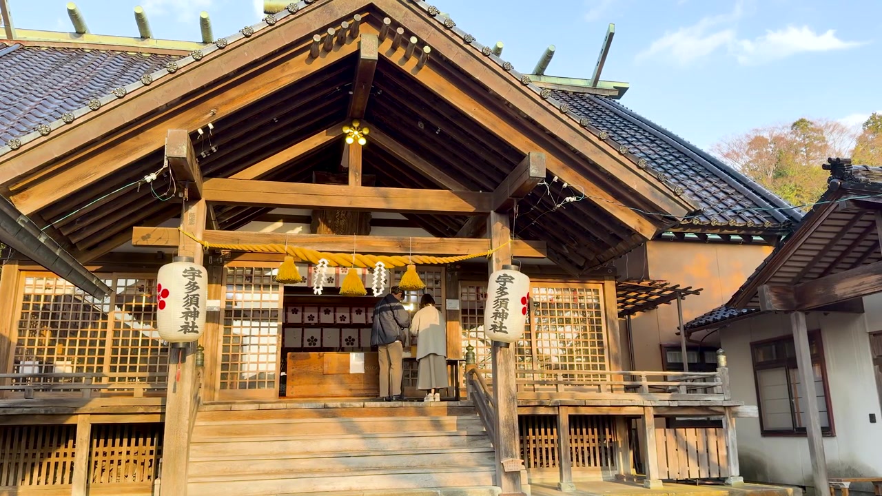 Static wide shot of a traditional wooden Shinto shrine with paper lanterns and shimenawa rope