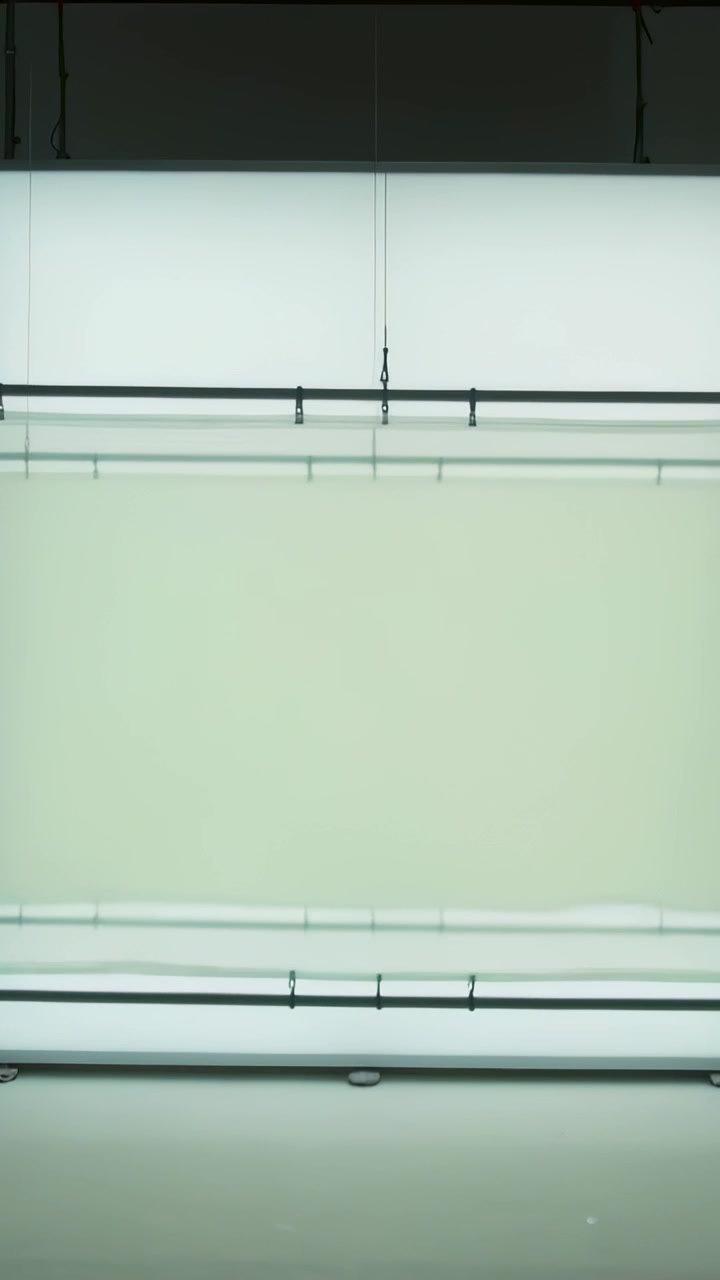 Vertical video: Shifting lightbox cycling blue to pink after cue in studio with rails and cable