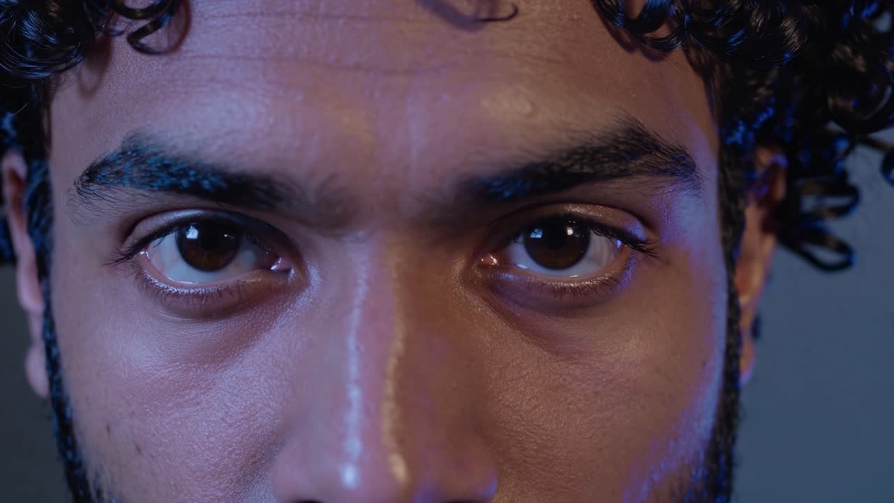 intenso retrato de primer plano que captura a un joven con el cabello rizado, revelando un paisaje emocional multifacético a través de interacciones faciales profundamente expresivas y matizadas y una mirada penetrante