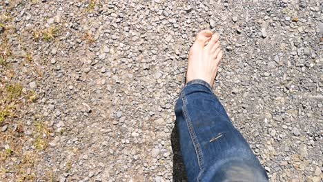 caminar descalzo por un camino de ripio, ver hacia abajo los pies y los pantalones vaqueros