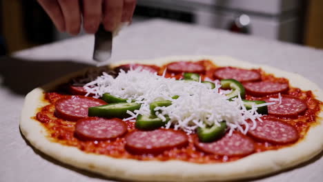 making pizza with salami, cheese, and peppers