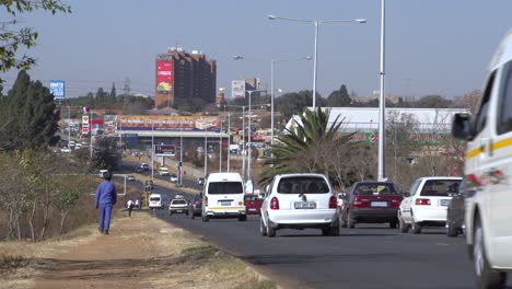 commuter cars and taxi vans travel along a main route in soweto township of johannesburg, south africa.