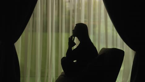 silhouette of a woman contemplating or feeling sad by a window