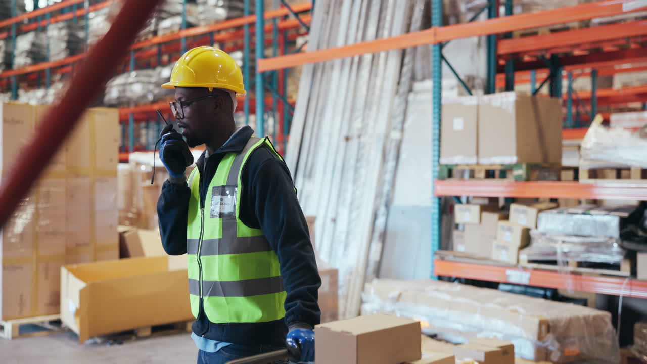 Warehouse Worker Talking on Walkie-Talkie While Pushing Hand Truck