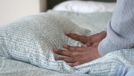 person adjusting pillow on bed