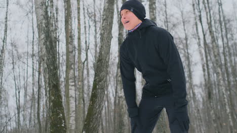 A-young-man-on-a-morning-jog-in-the-winter-forest-was-tired-and-stopped-to-catch-his-breath.-He-recovered-his-strength-and-overcame-fatigue-and-continued-to-run.-Perseverance-and-overcoming-weakness.-Push-forward
