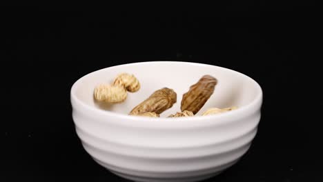 peanuts dropping into a white ceramic bowl