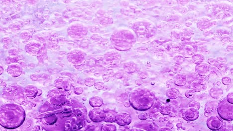 macro shot of violet bubbles in water floating right with yellow background