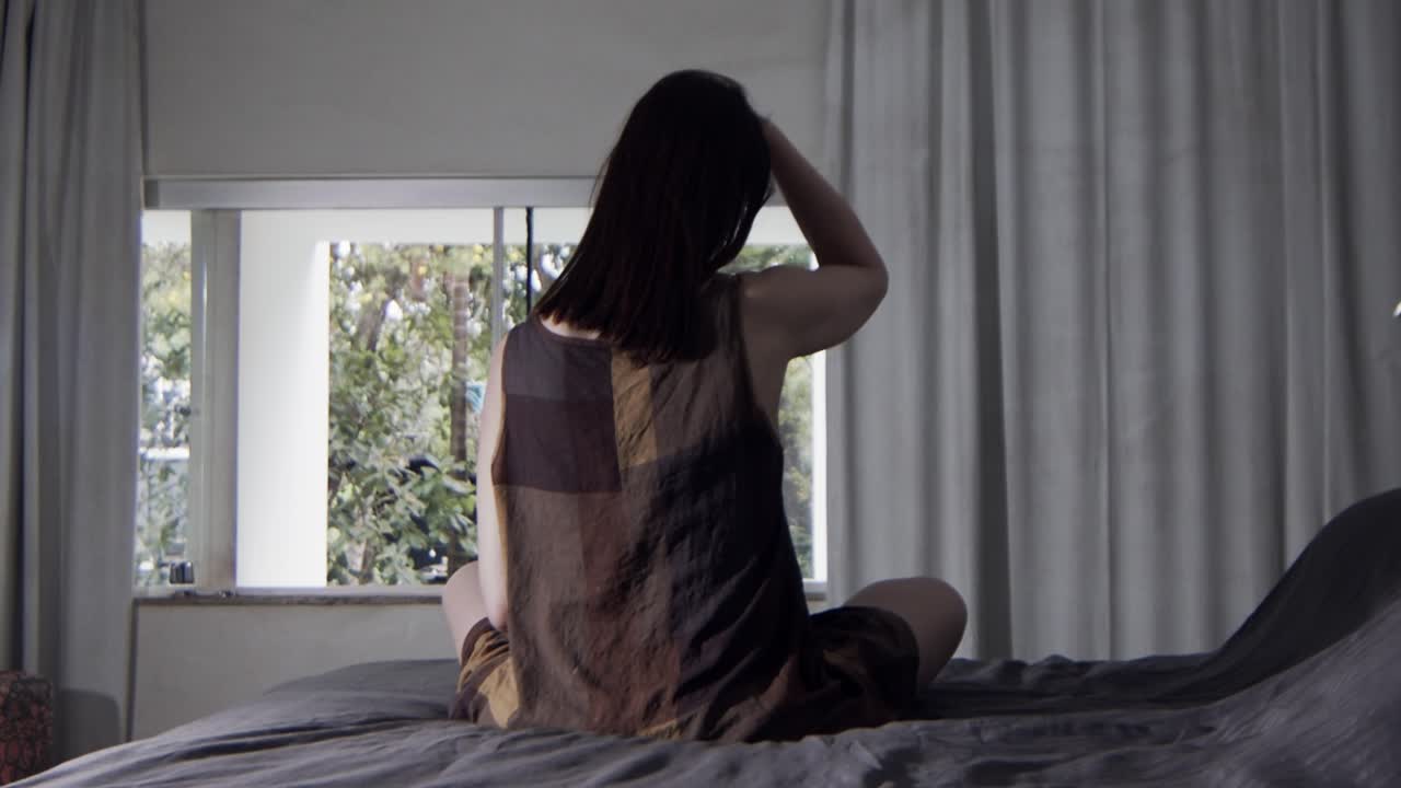 아침에 집에서 침대에 앉아 머리를 빗고 있는 여성의 뒷모습, 슬로우 모션