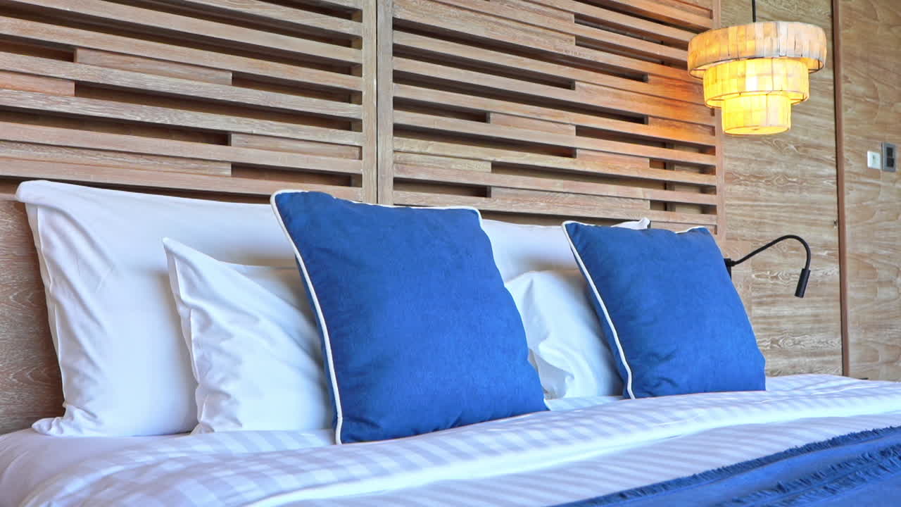 incline hacia abajo las almohadas decorativas azules que se sientan encima de la cama de una suite de hotel