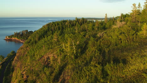 aerial flying over forest cliff revealing lake superior in north america