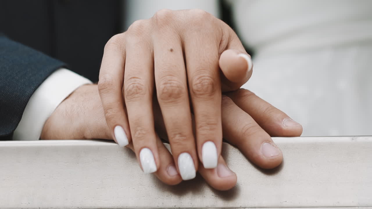 um casal recém-casado une as mãos de pé junto à grade da varanda