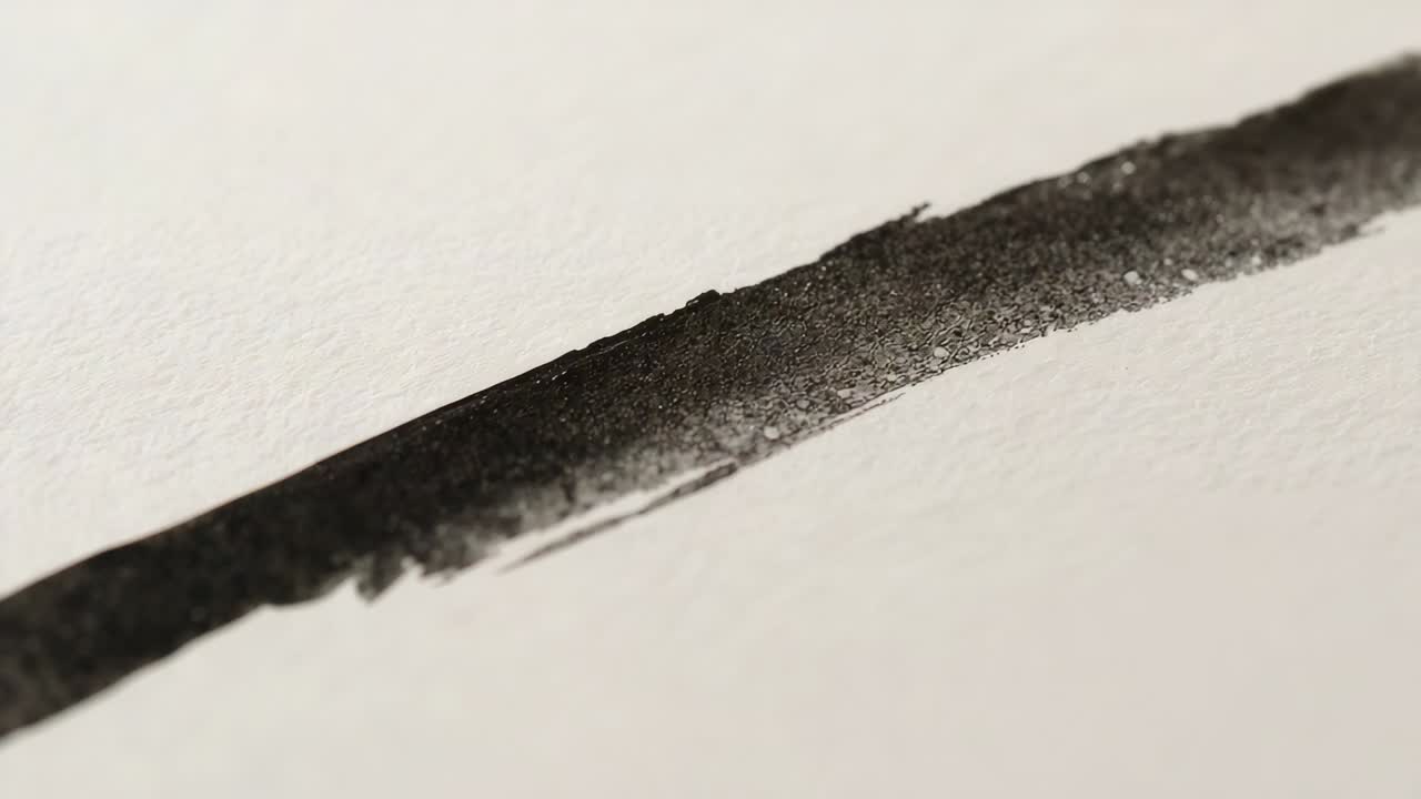 Zooming camera revealing single dark pigment stroke on textured white paper in studio for study