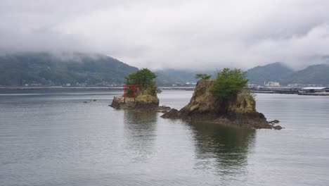 rain and cloudy day on etajima island, pan reveal of navy road shrine with torii