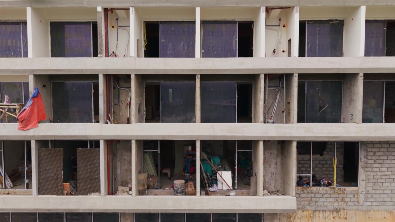 Facciata e finestre incompiute di un hotel appaiono mentre il drone si alza lentamente a Coron Town
