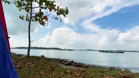 Tienda-De-Campaña-En-El-Campamento-De-Jelutong-Con-Una-Foto-Reveladora-De-La-Pintoresca-Isla-De-Pulau-Ubin-En-Un-Día-Nublado,-En-Singapur