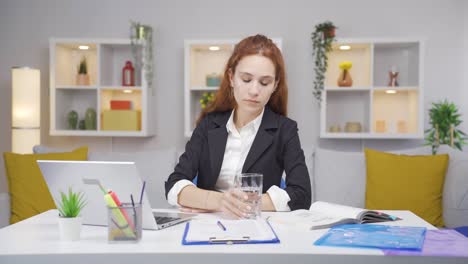 una mujer que trabaja en una oficina en casa tiene sensibilidad dental.