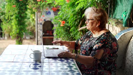 aged female speaking on phone at table with laptop