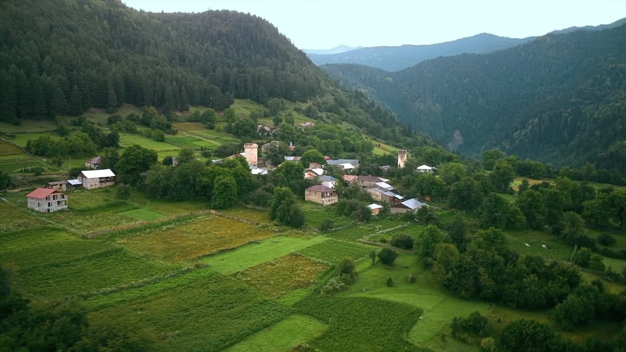 Vue aérienne d’un village en Géorgie. Vallée, bâtiments, montagnes et pentes de collines couvertes de verdure