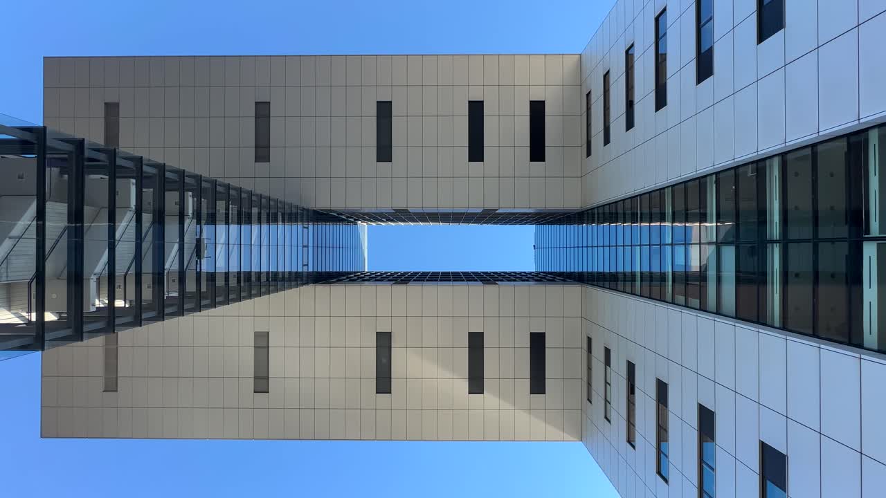 Vista architettonica simmetrica tra moderni edifici adibiti a uffici che formano una cornice geometrica con cielo azzurro al centro - Colonia, Germania