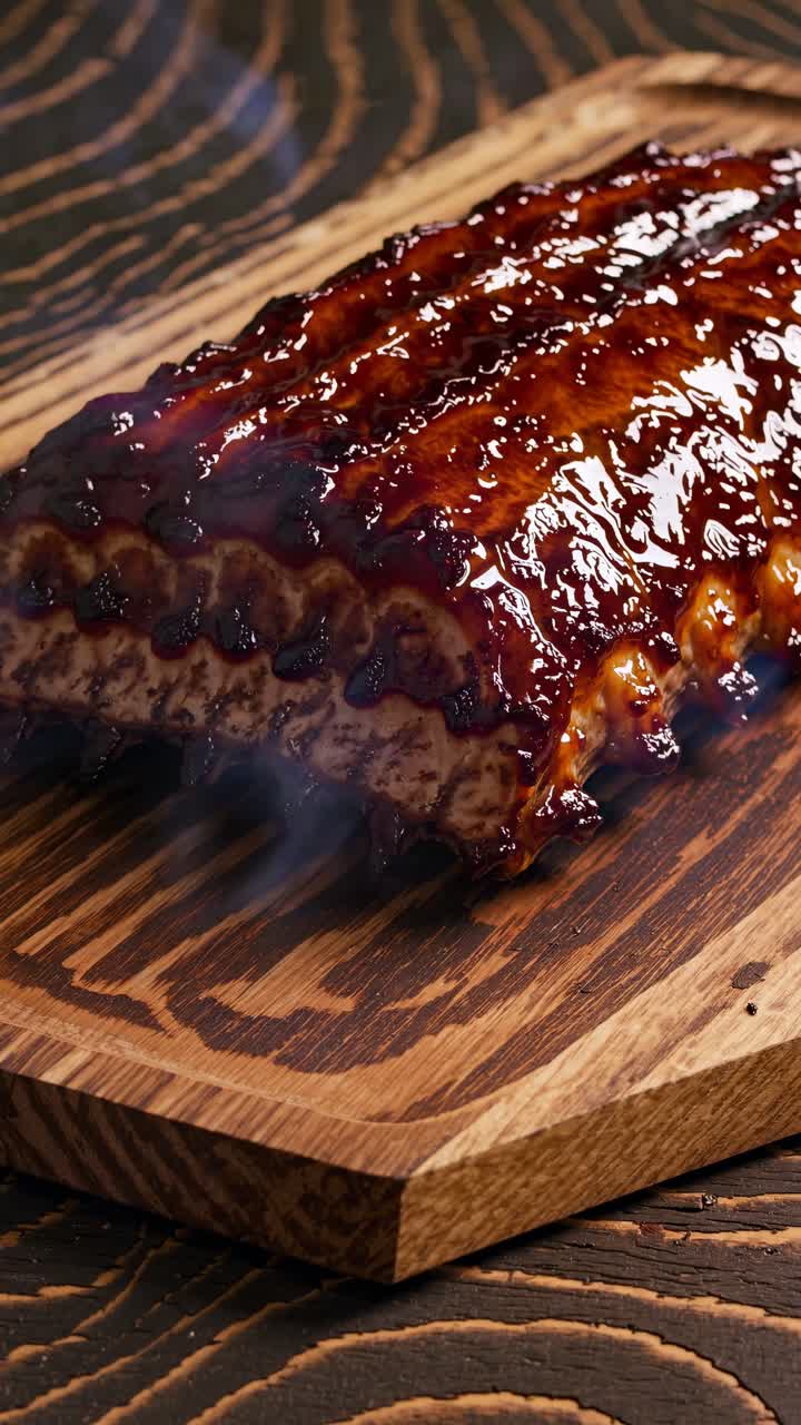 Primer plano a contrapicado de costillas glaseadas sobre una tabla de madera, capturando el vapor y el brillo, perfecto