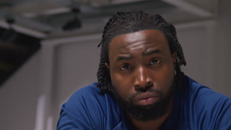 close up portrait of determined male athlete sport training in gym sitting and concentrating in changing room with focused expression