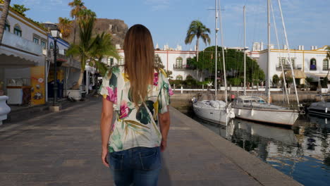 gimbal shot following young woman walking on marina in canary islands