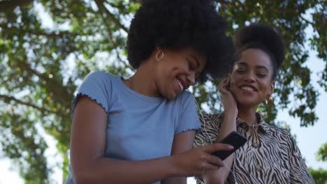 Two-mixed-race-women-listening-music-in-park