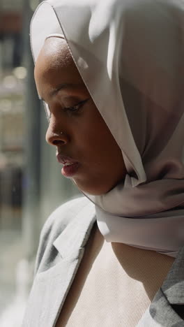 black woman in silk hijab holds smartphone going up in trade mall elevator closeup slow motion. muslim lady does shopping. public place for rest and entertainment