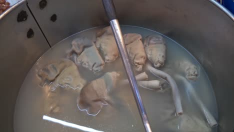 stew pork stomach slow cooked in big pot at food booth documentary